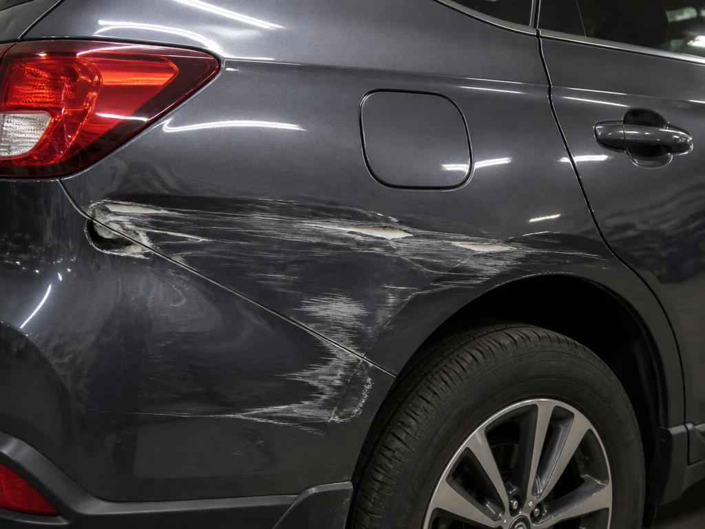 Scratched and scuffed rear quarter panel on a grey SUV before repair